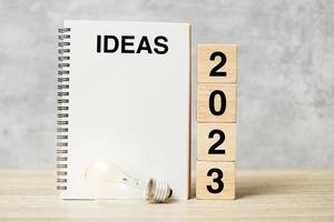 2023 text wood cube blocks and IDEAS word with lightbulb on table. New Year New Ideas, Creative, Innovation, Imagination, inspiration, Resolution, Strategy and goal concept photo