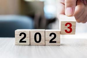hand flipping block 2022 to 2023 text on table. Resolution, strategy, plan, goal, motivation, reboot, business and New Year holiday concepts photo