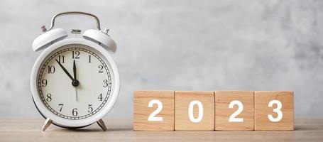 Happy New Year with vintage alarm clock and 2023 block. Christmas, New Start, Resolution, countdown, Goals, Plan, Action and Motivation Concept photo