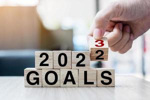 hand flipping block 2022 to 2023 GOAL text on table. Resolution, strategy, plan, motivation, reboot, business and New Year holiday concepts photo