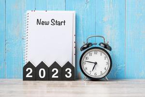 2023 Happy New Year with New start, black retro alarm clock and wooden number.Resolution, Goals, Plan, Action and Mission Concept photo