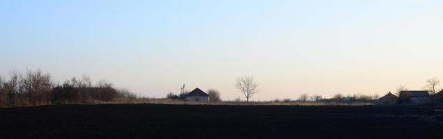 Dawn in the village. A minimalistic photo with a horizon line on which there is an apartment house and a tree