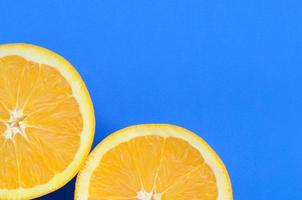 Top view of a several orange fruit slices on bright background in blue color. A saturated citrus texture image photo