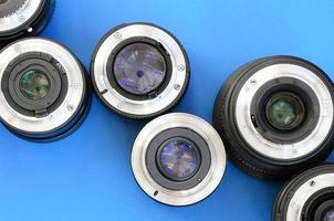 Several photographic lenses lie on a bright blue background. Space for text photo