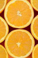 Top view of a several orange fruit slices on bright background in orange color. A saturated citrus texture image photo