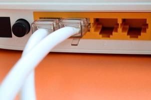 The Internet cable plugs are connected to the Internet router, which lies on a bright orange background. Items required for Internet connection photo