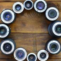 Several photographic lenses lie on a brown wooden background. Space for text photo