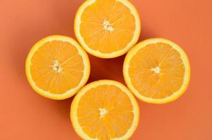 Top view of a several orange fruit slices on bright background in orange color. A saturated citrus texture image photo