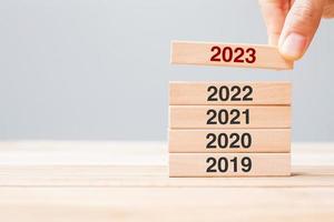 2023 block over 2022 and 2021 wooden building on table background. Business planning, Risk Management, Resolution, strategy, solution, goal, New Year New You and happy holiday concepts photo