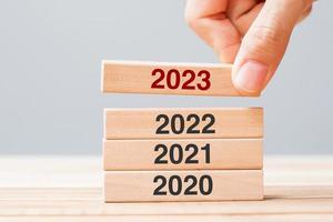 2023 block over 2022 and 2021 wooden building on table background. Business planning, Risk Management, Resolution, strategy, solution, goal, New Year New You and happy holiday concepts photo
