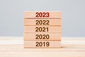 2023 block over 2022 and 2021 wooden building on table background. Business planning, Risk Management, Resolution, strategy, solution, goal, New Year New You and happy holiday concepts photo