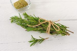 Rosemary bound and dry herbs on a wooden table photo