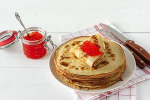 crepes rusos tradicionales blini apilados en un plato con caviar rojo sobre fondo de madera. Maslenitsa comida tradicional del festival ruso. comida rusa, cocina rusa. de cerca. foto