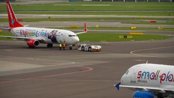 amsterdam, holanda, 29 de julho de 2017 - smallplanet airlines airbus a320 ly spa taxiando após o pouso e corendon boeing 737 push back, shiphol airport, amsterdam, holland video
