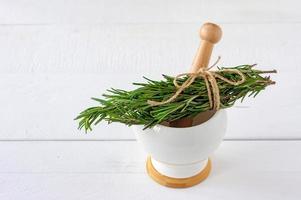 Rosemary bound on a wooden table lie on a pounder photo