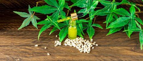 cuentagotas con aceite de cbd sobre fondo de hojas de cáñamo, aceite de cannabis - concepto de marihuana medicinal foto