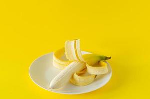 Ripe banana on black plate on yellow background. Tropical fruits for eating photo