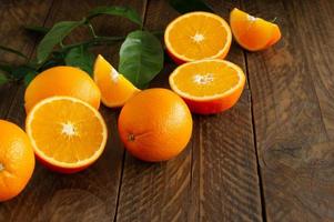 naranjas frescas con aleros verdes sobre fondo rústico de madera con espacio de copia.