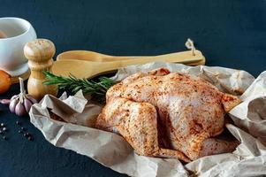 Fresh raw chicken on baking paper and spices for cooking. photo