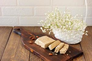 Slised sunfower halva dessert on a serving wooden board on a table. Sweet oriental dessert from nuts and seeds photo