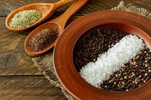 Assorted spices in a plate, spoons and bowls on wooden background photo