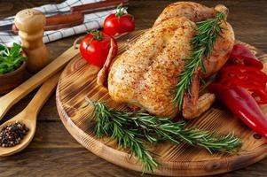 baked chicken with a golden crust with vegetables and herbs on a wooden background
