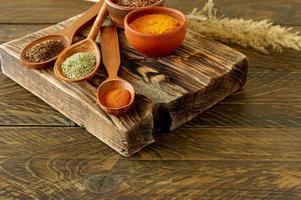 Powder spices on spoons on wooden background photo