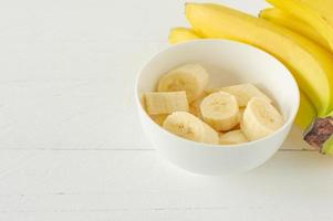 Ripe bananas cut in white bowl for eating. Healthy snack or breakfast concept photo