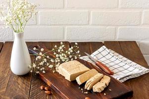 Slised sunfower halva dessert on a serving wooden board on a table. Sweet oriental dessert from nuts and seeds photo