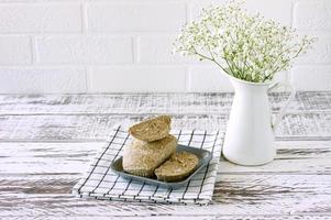 halva de maní en un plato sobre una mesa de madera blanca. postre oriental de nueces y semillas con jarabe de azúcar foto