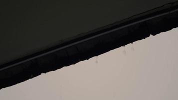 chuva e telhado. chuva caindo do telhado. gotas de chuva caem de um telhado para baixo. video