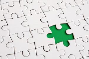 Close-up texture of a white jigsaw puzzle in assembled state with missing elements forming a green pad for text. Copy space photo