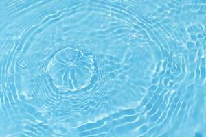 Defocus blurred transparent blue colored clear calm water surface texture with splash, bubble. Shining blue water ripple background. Surface of water in swimming pool. Blue bubble water shining. photo