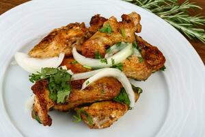 Chicken wings on the plate and wooden background photo