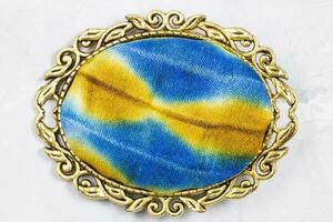 brass brooch with hand-colored silk batik on gray photo