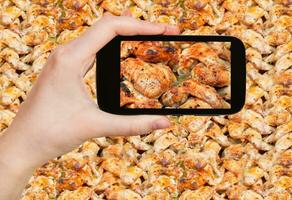 tourist taking photo of roasted chicken wings