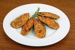 Baked mussels on the plate and wooden background photo