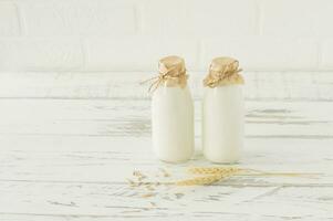 Oat milk in glass bottles on a wooden table. Homemade organig proteing milk. photo