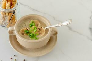 Mushroom cream soup with croutons, herbs and spices over marble background photo