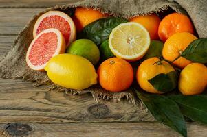Assortment of citrus fruits in rustic style, Oranges, grapefruits, lemons and limes on burlap on wooden background. photo