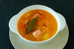 homemade soup with salmon with bread sticks on back concrete background photo