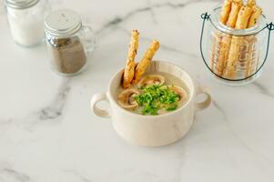 Mushroom cream soup with croutons, herbs and spices over marble background photo