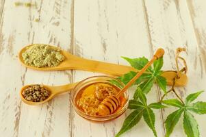 Honey dipper with Cannabis leaves, CBD Hemp honey, seeds and powder. Alternative medicine ingredients on wooden table photo