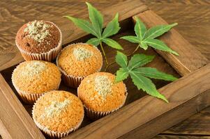 muffins de magdalenas de marihuana y hojas de cannabis en una caja de madera. cocinado en casa. comida dulce con cáñamo foto