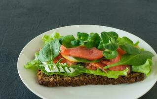 Sandwich with smoked salmon soft cheese, lattice and lemon. Concept for a tasty and healthy meal. Food on a plate. photo