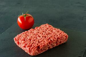 Raw minced beef meat on a slate with tomato. photo