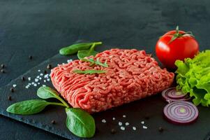 Raw minced beef meat on a slate with leaves and spices. photo