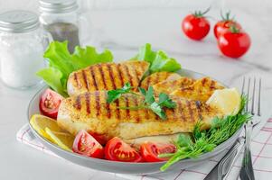 Grilled chicken breasts served on a plate with salad and vegetables. Dietary food photo