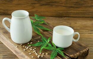 Cannabis herbal vegan leche sin gluten y sin lactosa y hojas de cannabis sobre mesa de madera foto