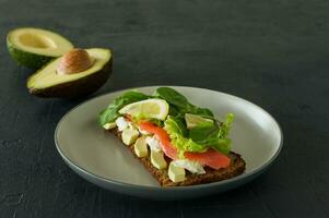 Sandwich with smoked salmon soft cheese, lattice and avocado. Concept for a tasty and healthy meal. Food on a plate. photo